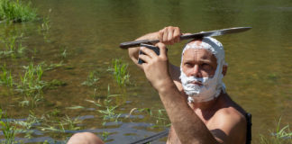 crazy or mad man shaves his head with machetes.