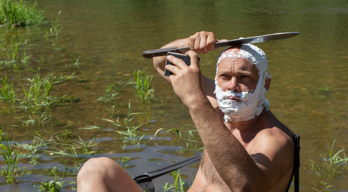 crazy or mad man shaves his head with machetes.