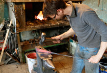 Blacksmith forging red-hot metal with hammer.