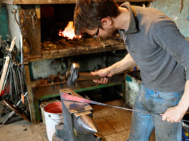 Blacksmith forging red-hot metal with hammer.