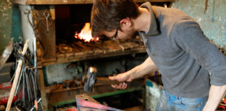 Blacksmith forging red-hot metal with hammer.