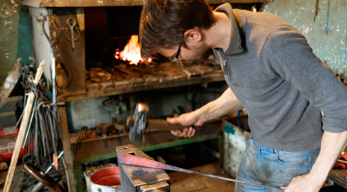 Blacksmith forging red-hot metal with hammer.